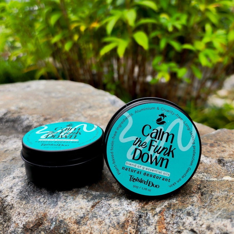 A jar of 'Calm the Funk Down' natural deodorant cream placed on a rock, with its lid off, showing the label with blue and white colors. The product is awarded the Beauty Insiders' Choice Award for 2020 and 2021.