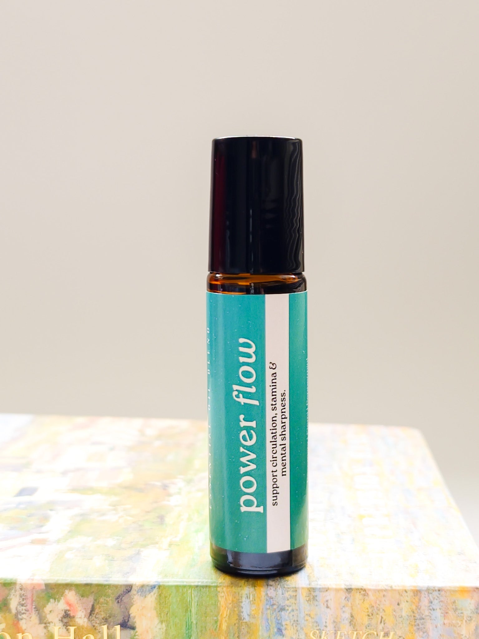Roll-on bottle labeled 'power flow' on a textured surface with a neutral background