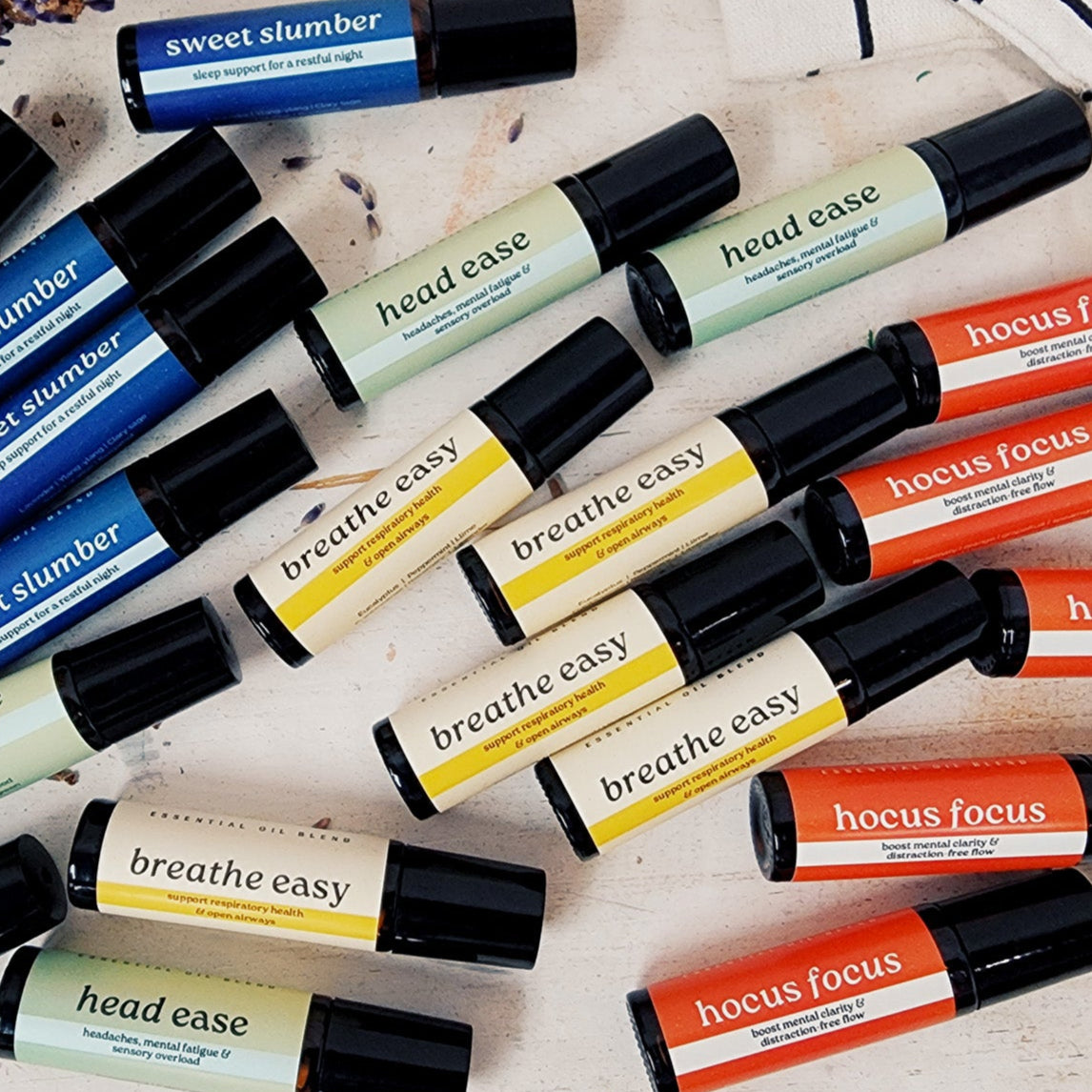 Collection of small rollerball bottles with various labels on a light surface.