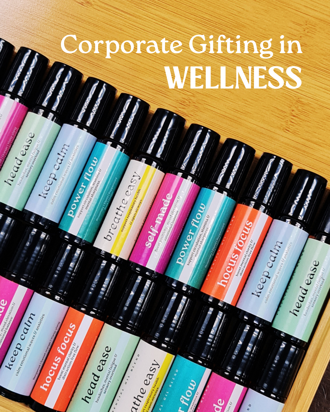 Row of wellness rollerball bottles with colorful labels on a wooden surface, text 'Corporate Gifting in Wellness' above.